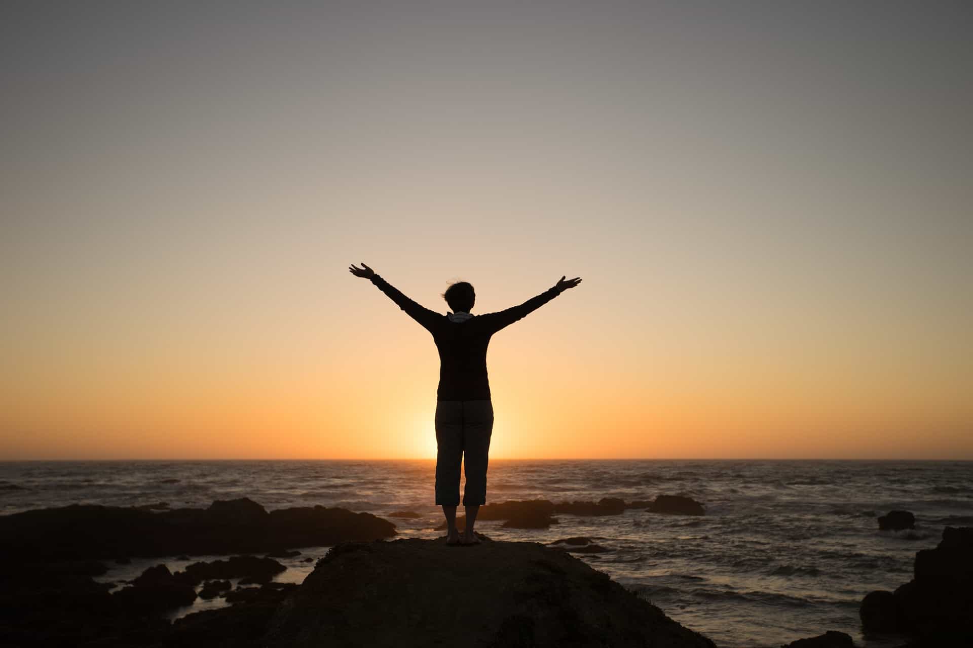 Arms outstretched beside ocean