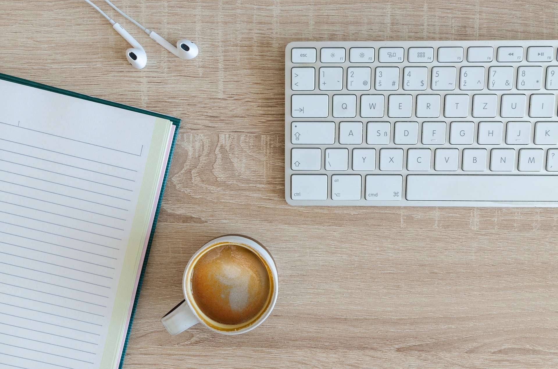 Keyboard, coffee, notebook, earbuds