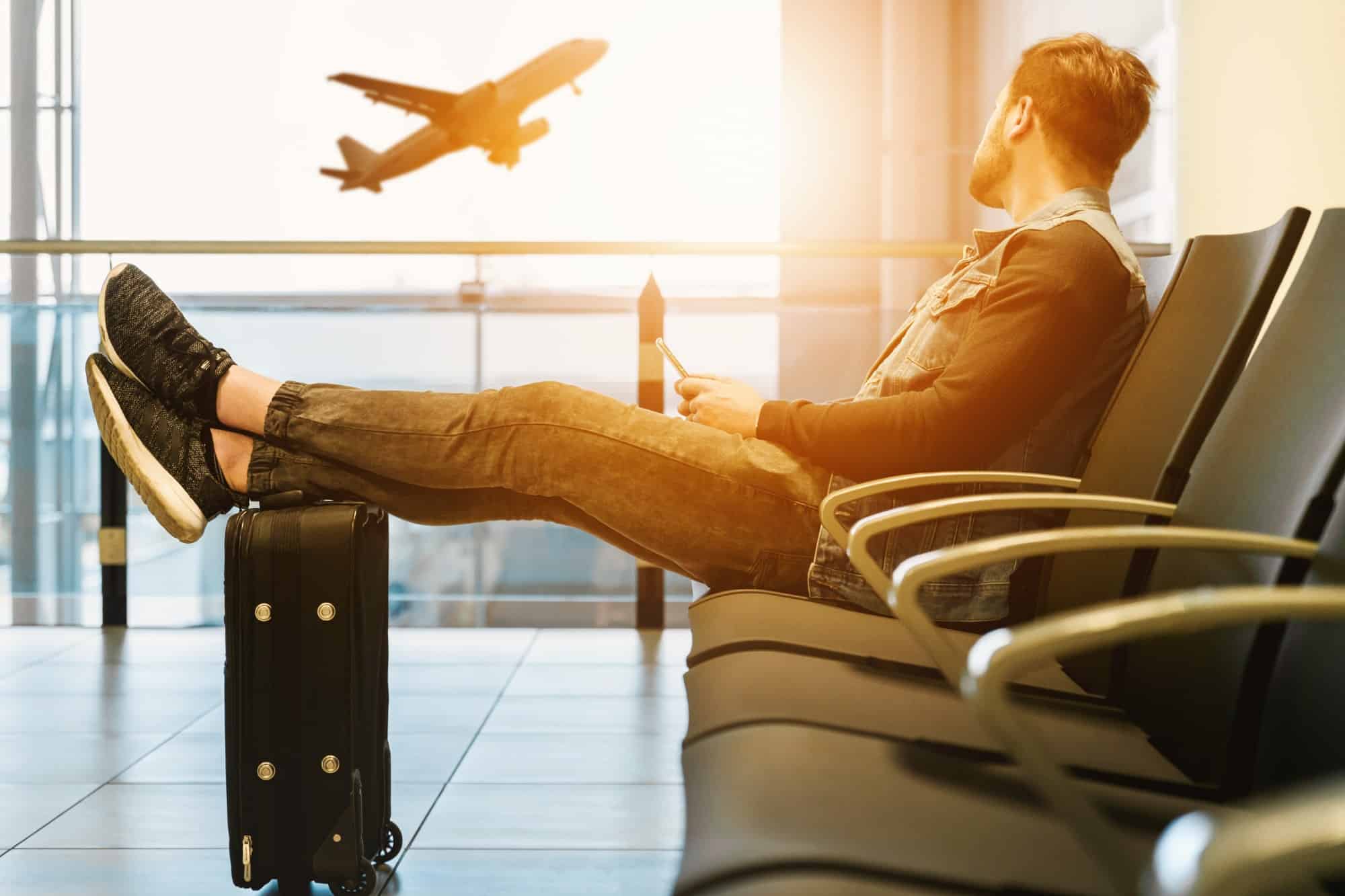 Man looking out airport window at plane