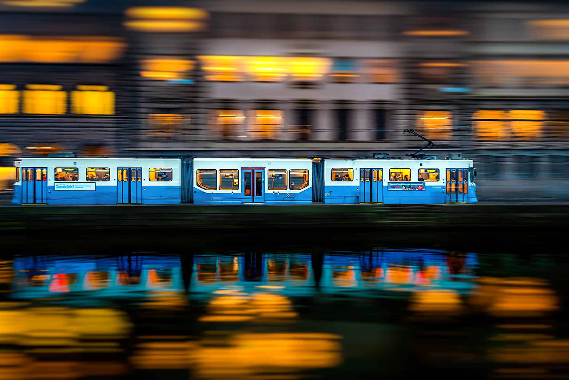 Side view of train with two carriages and motion-blurred buildings behind