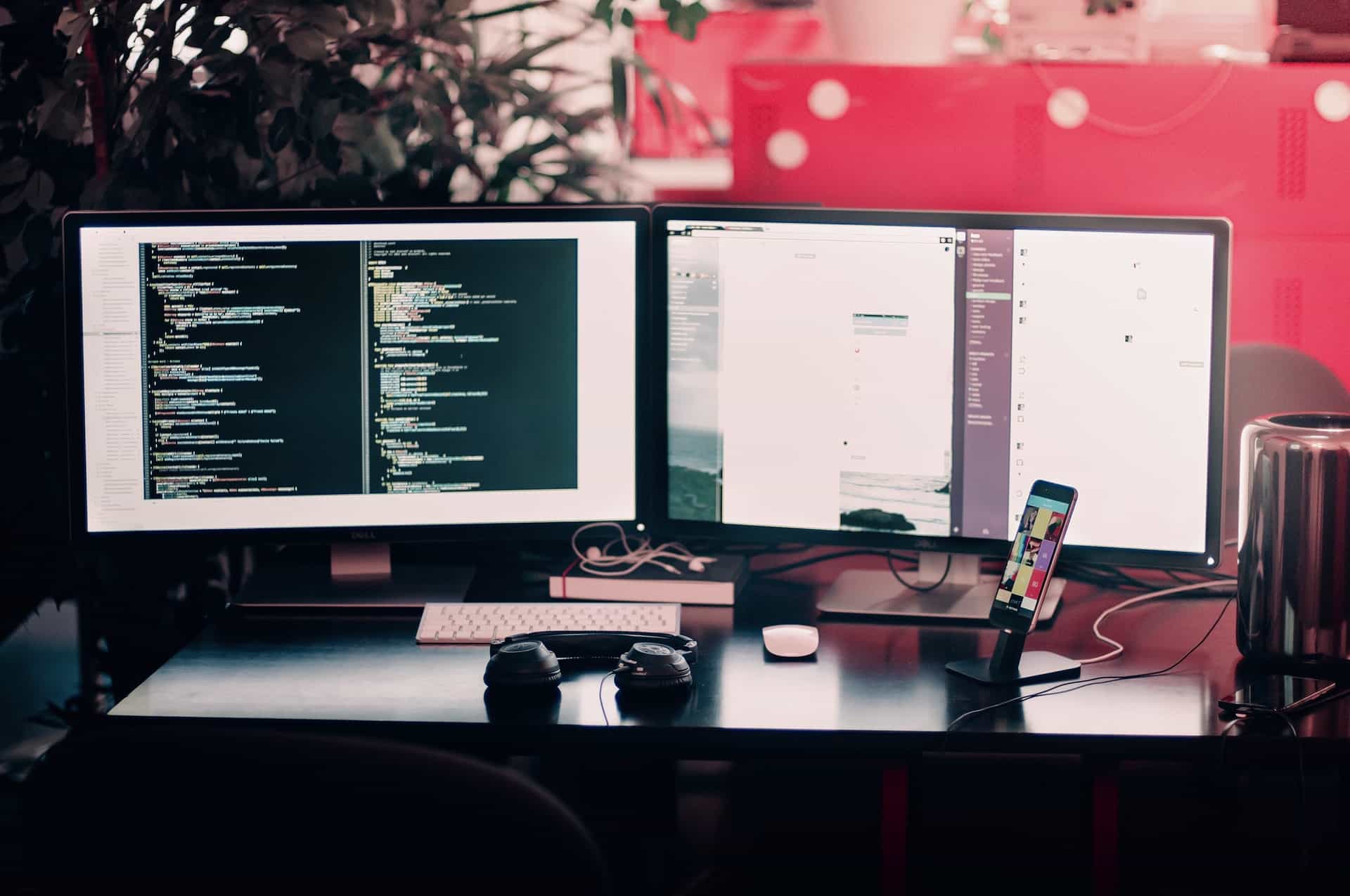 Two monitors, phone, and headphones on desk